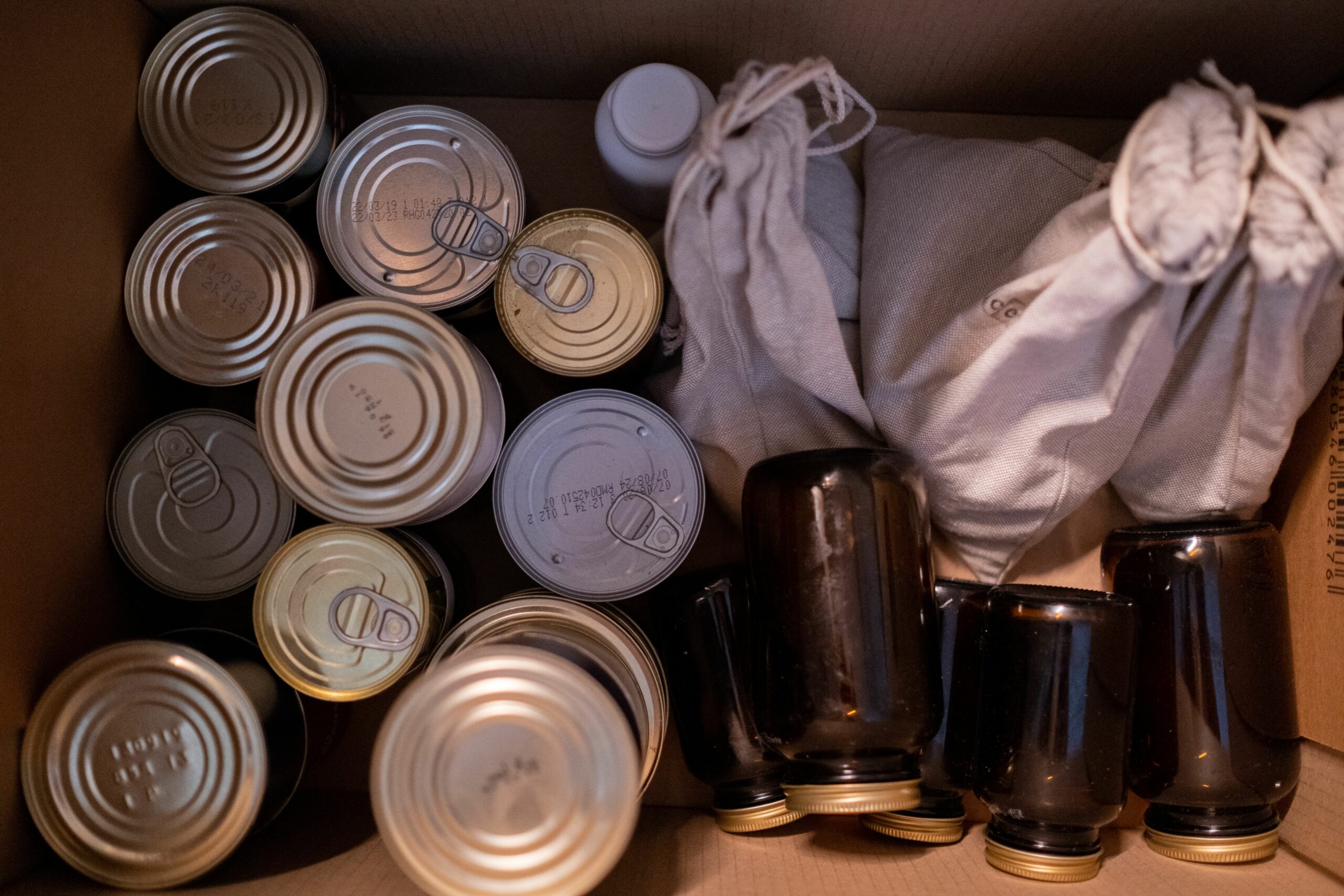 Latas de conserva y tarros de vidrio colocados juntos en una caja