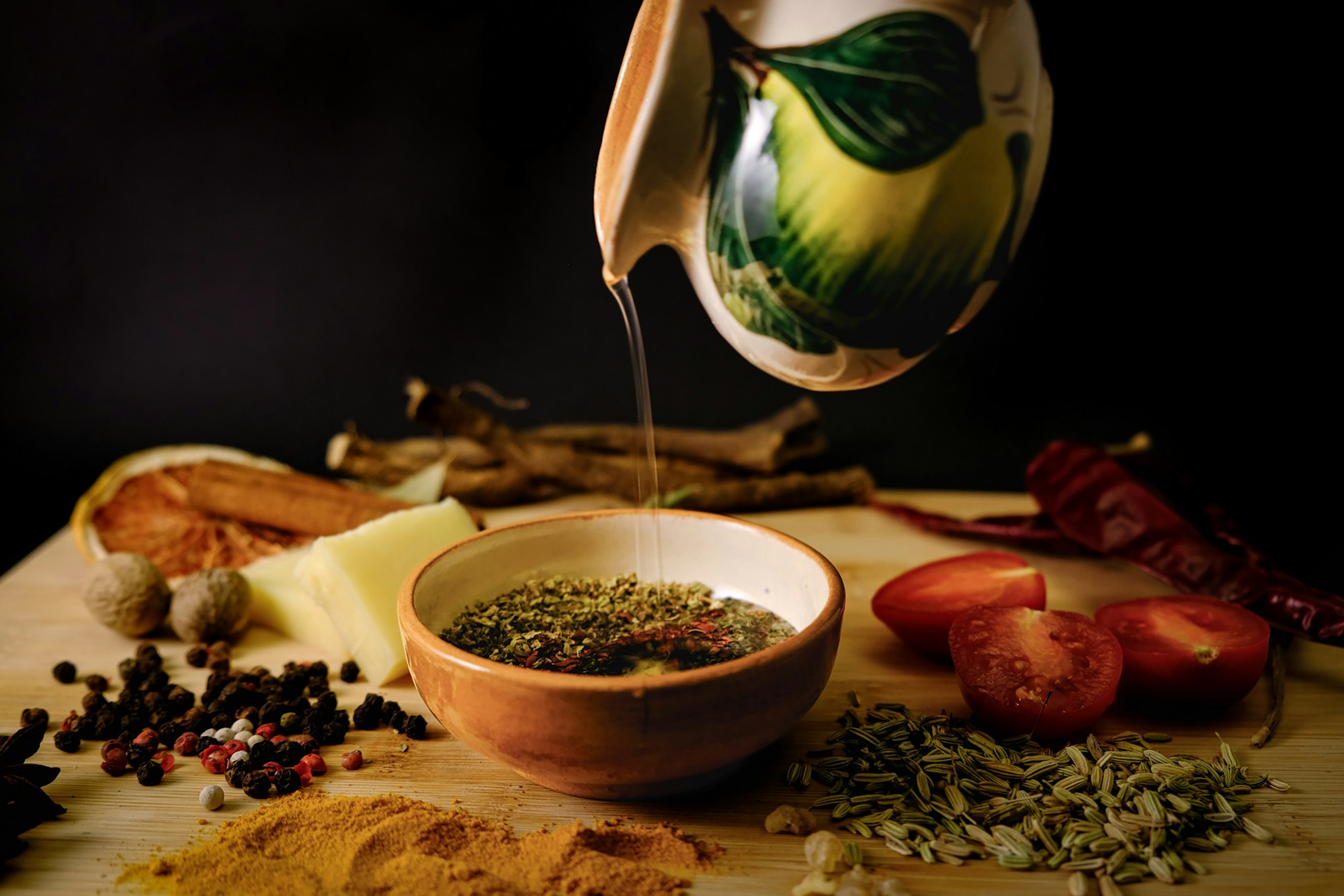 Aceite de oliva vertiéndose sobre un cuenco con hierbas y especias