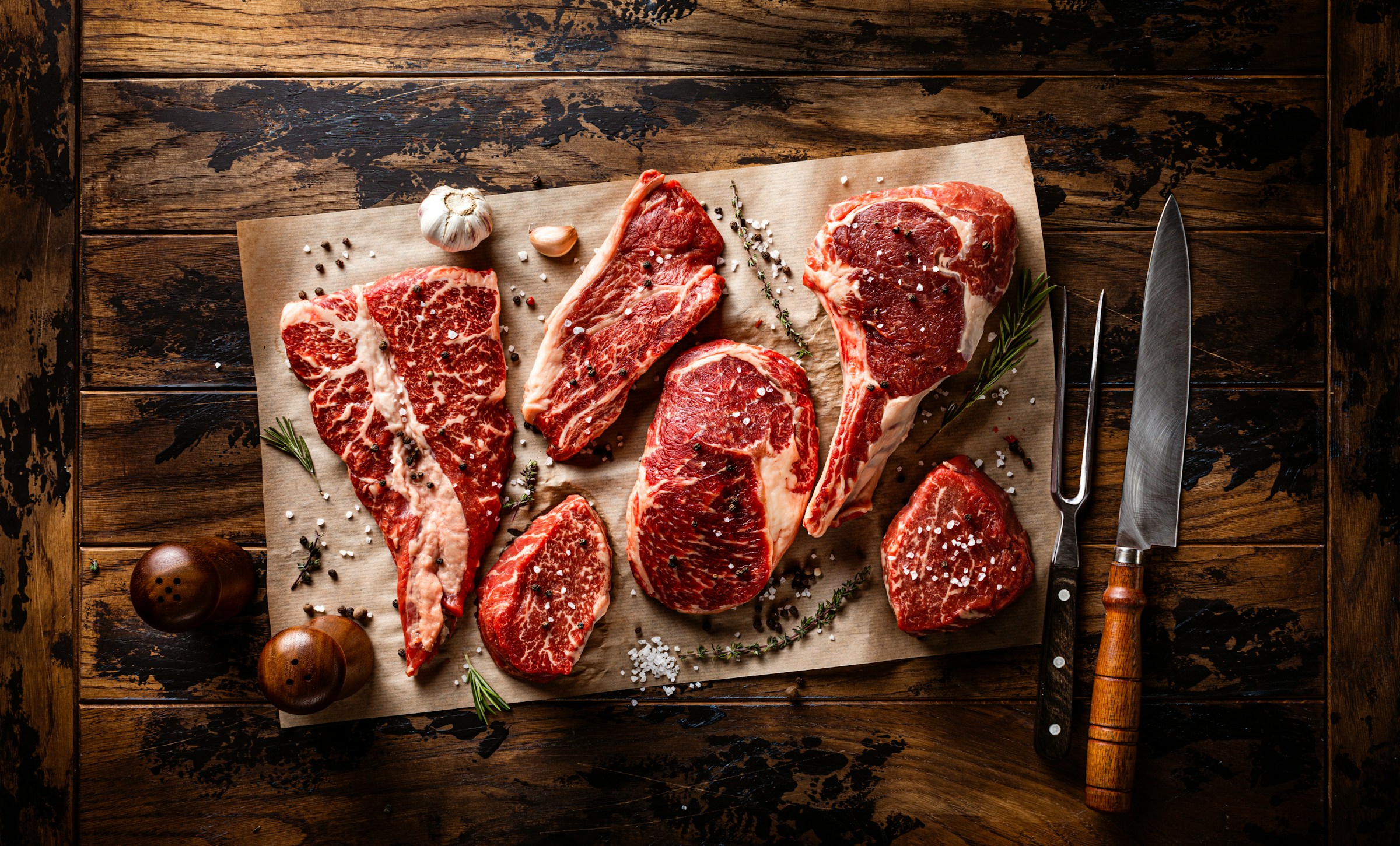 Surtido de cortes de carne fresca cruda sobre una tabla de madera para preparar una barbacoa