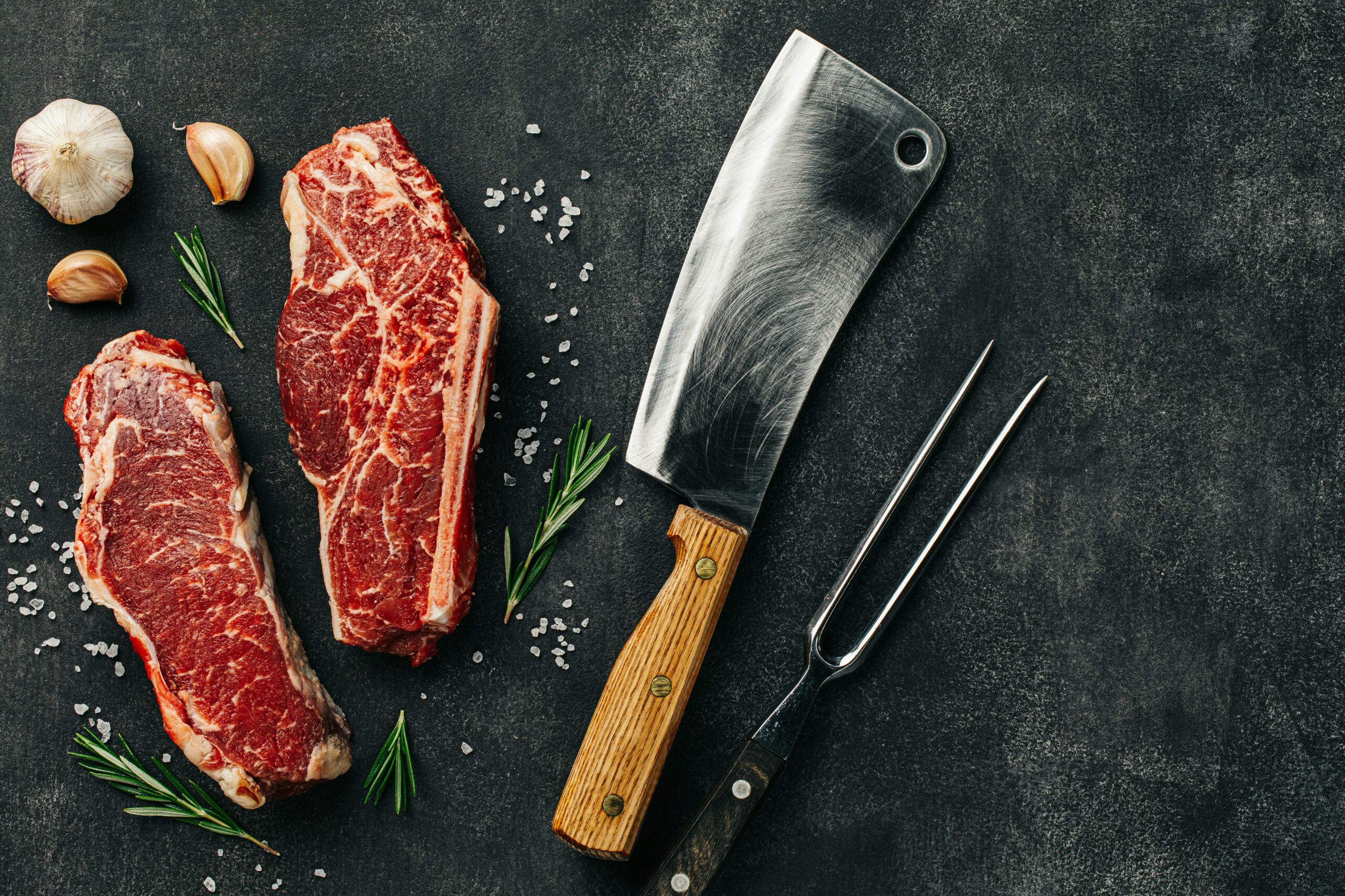 Dos cortes de vacuno crudo sobre una mesa de carnicero para comparar diferentes perfiles de carne