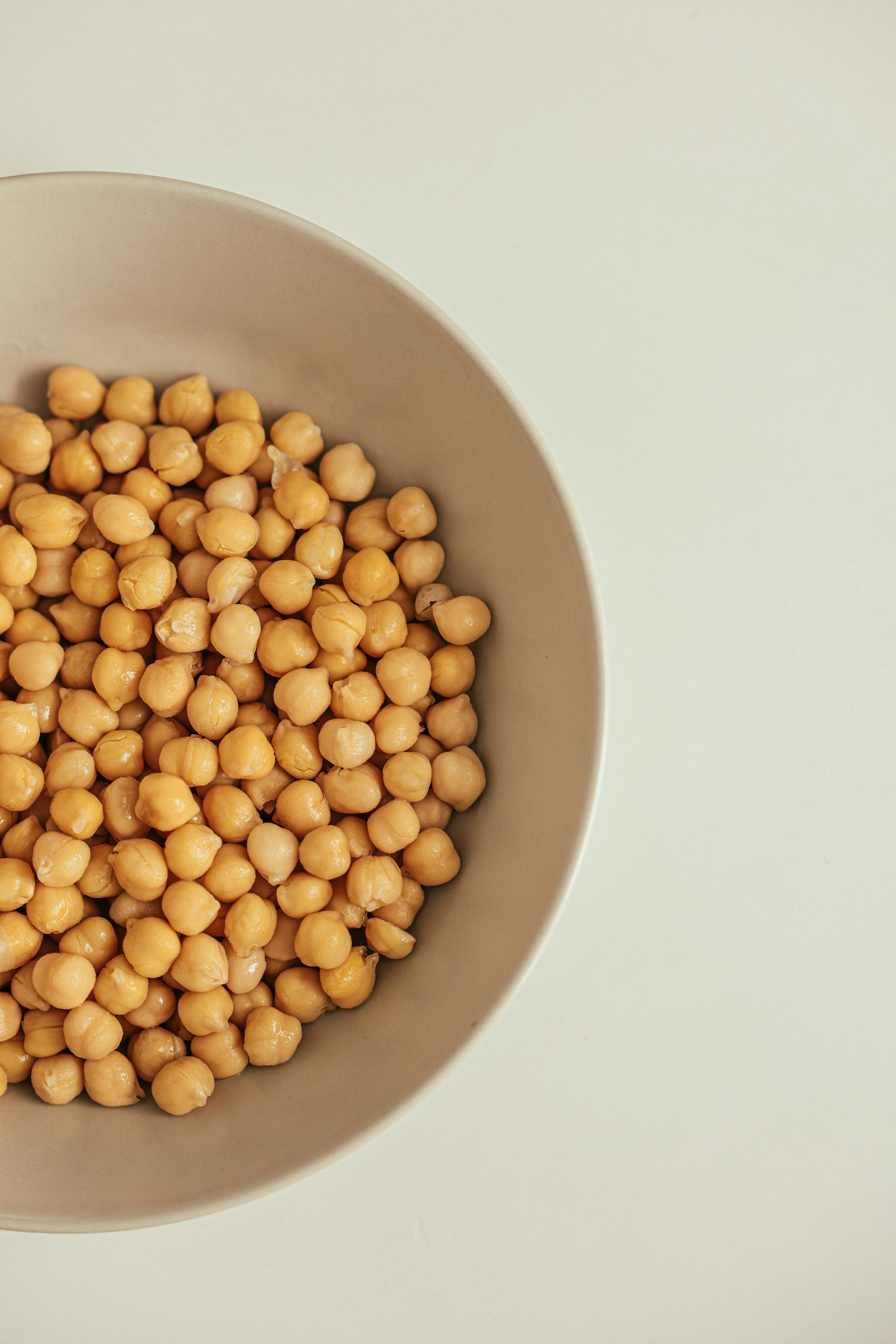 Garbanzos cocidos en un bol beige sobre un fondo claro y minimalista