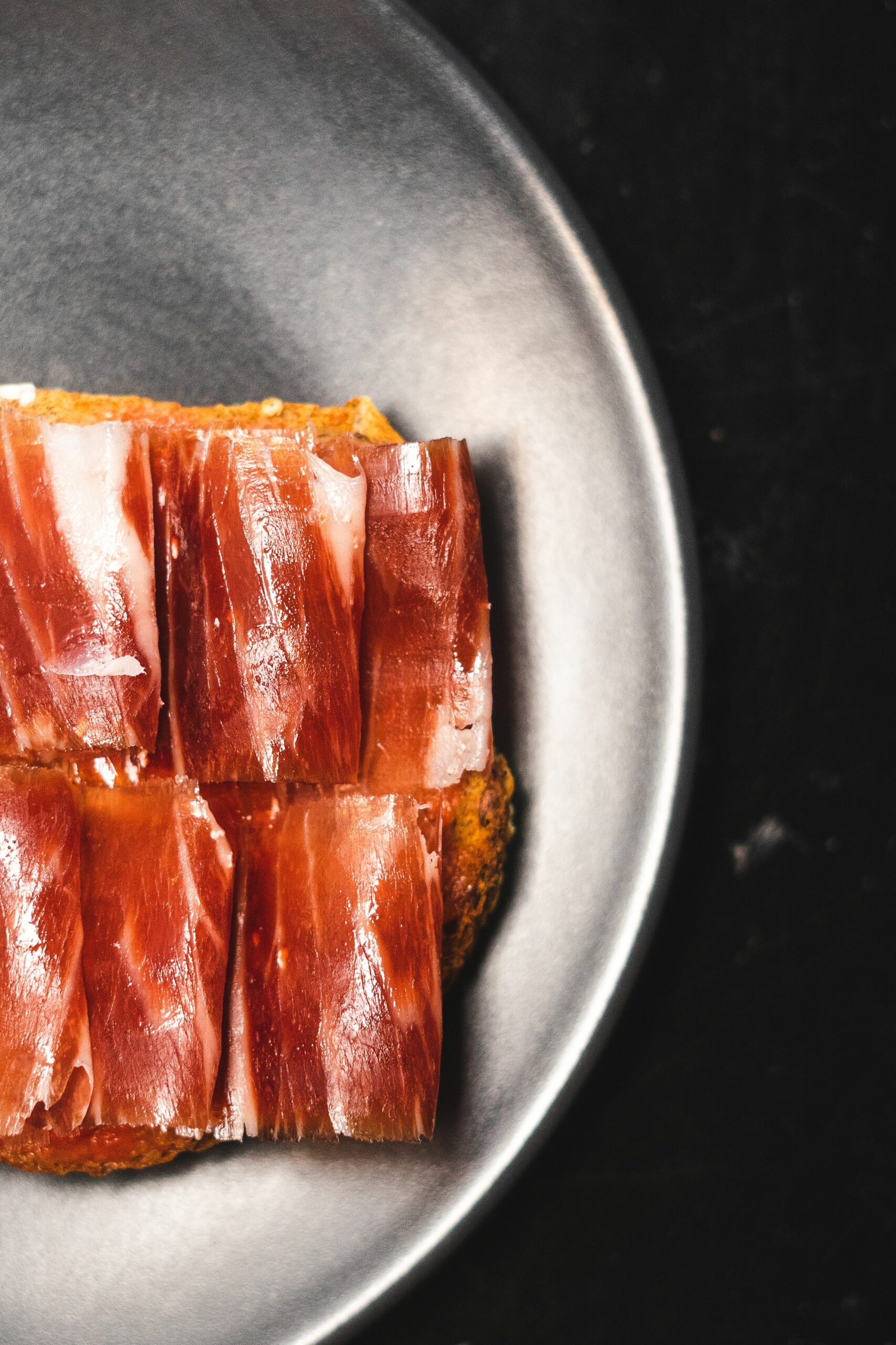 Lonchas de jamón sobre pan tostado con vetas de grasa visibles