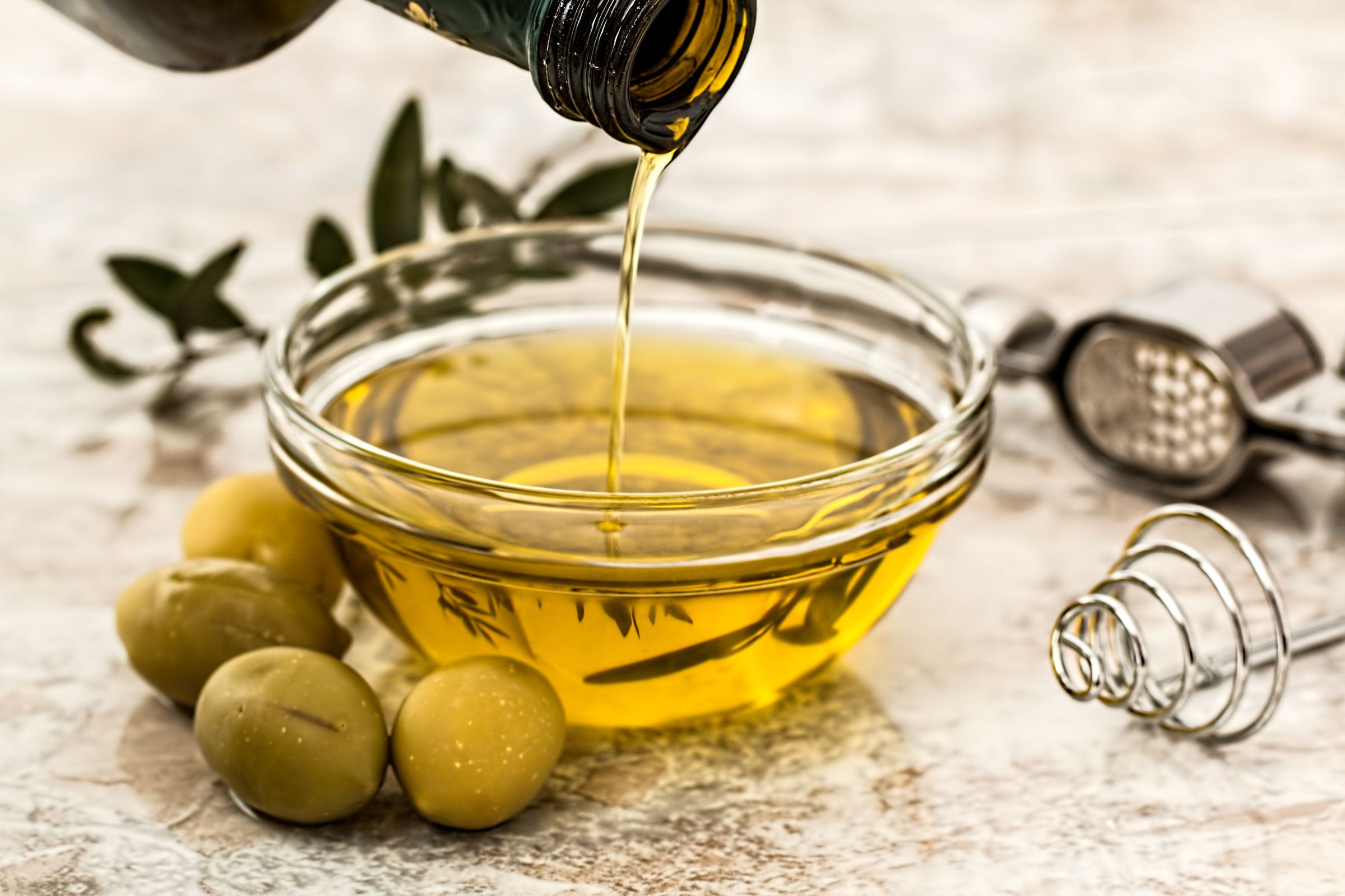 Aceite de oliva vertiéndose en un recipiente de vidrio sin envase de marca