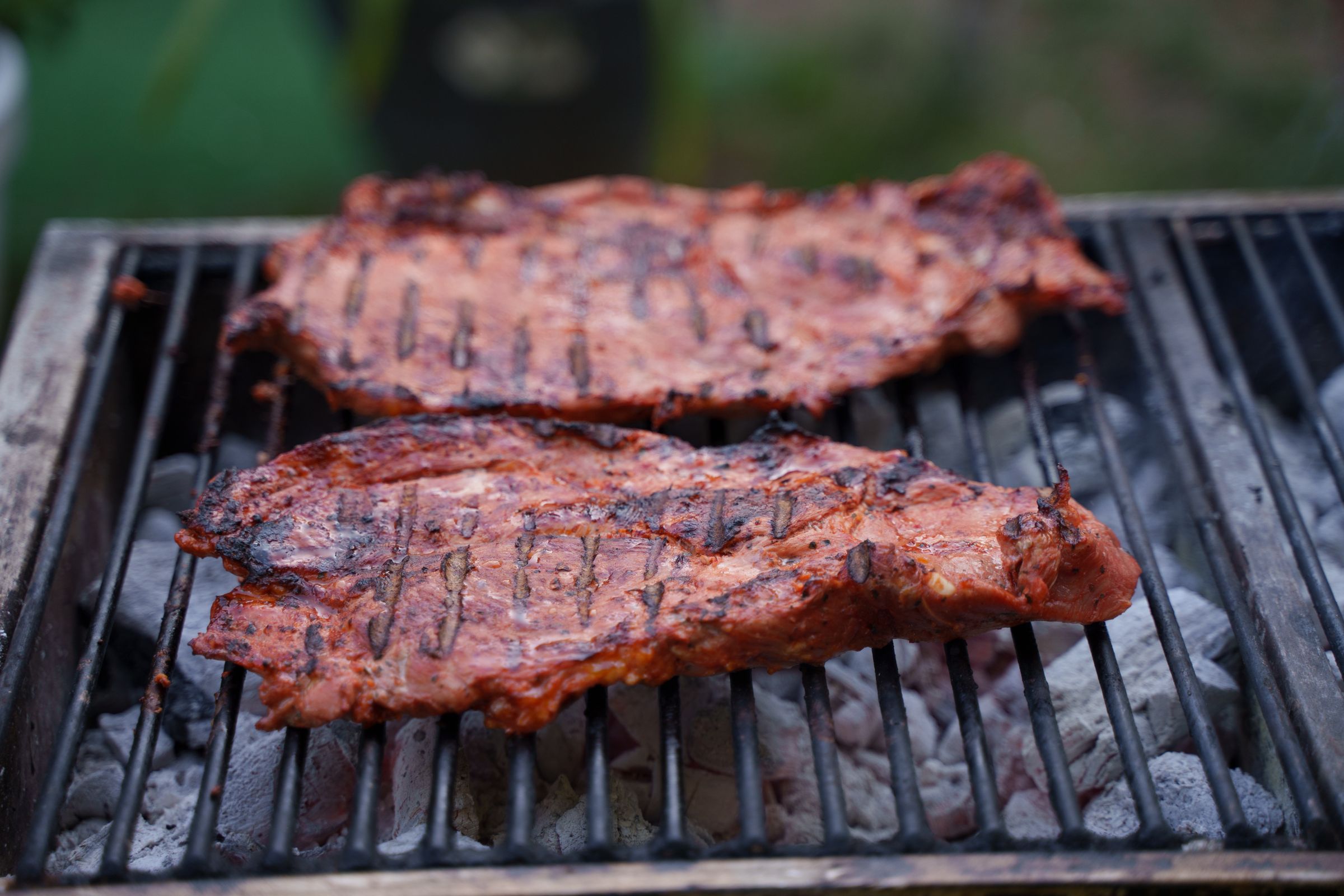 Chuletones cocinándose sobre una parrilla de carbón caliente
