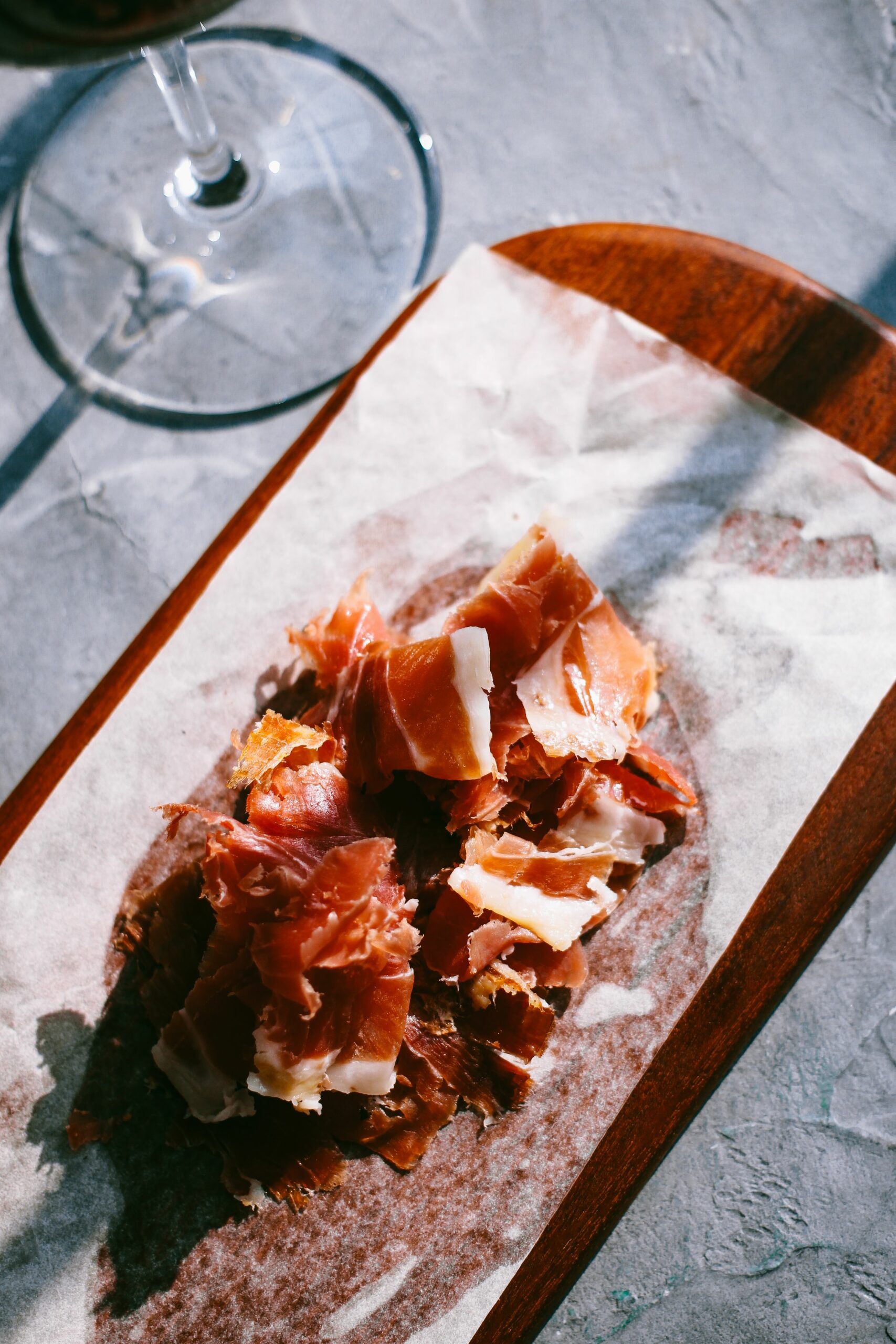 Lonchas de jamón curado recién cortadas sobre una tabla de madera