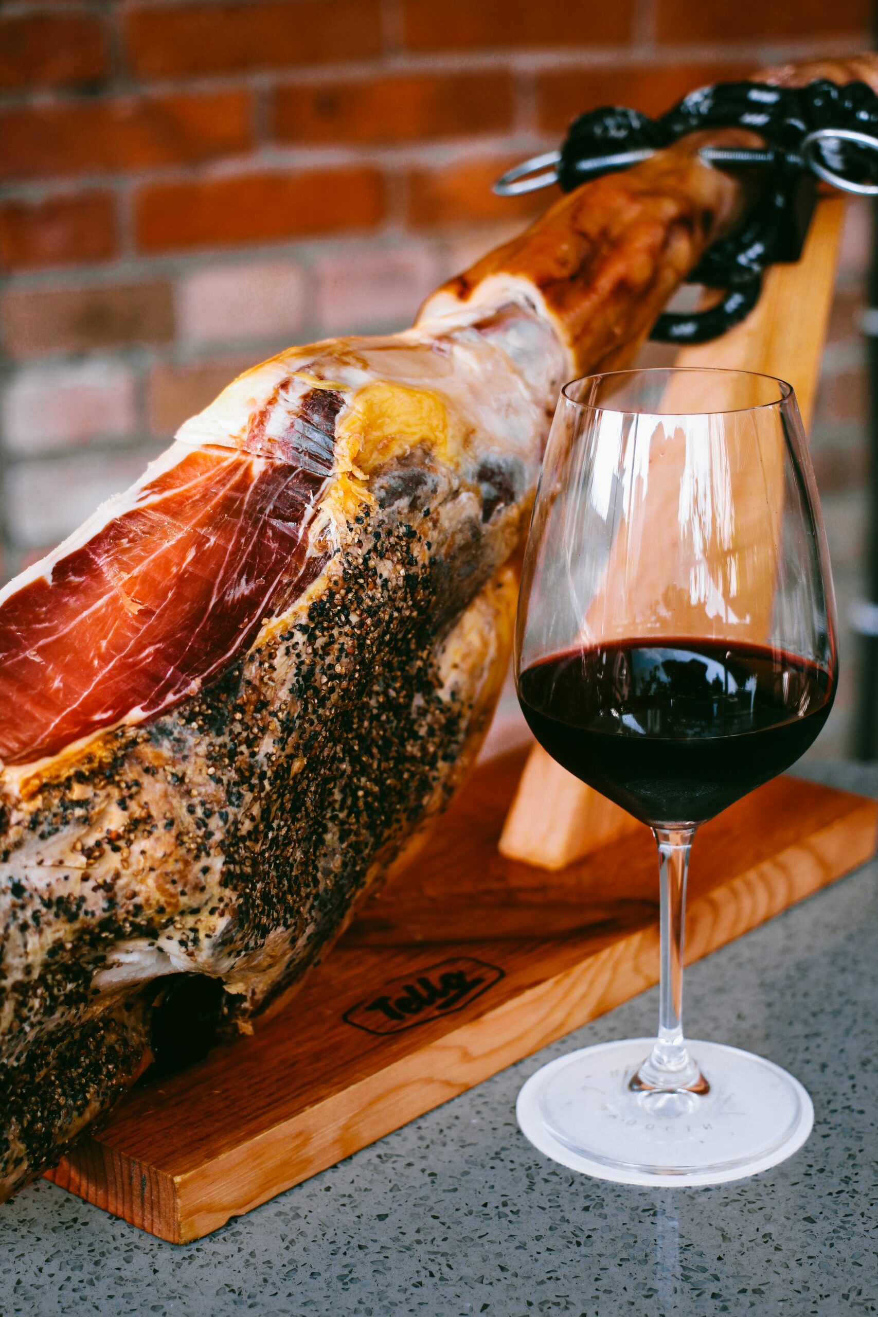 Pieza de jamón curado en jamonero junto a una copa de vino