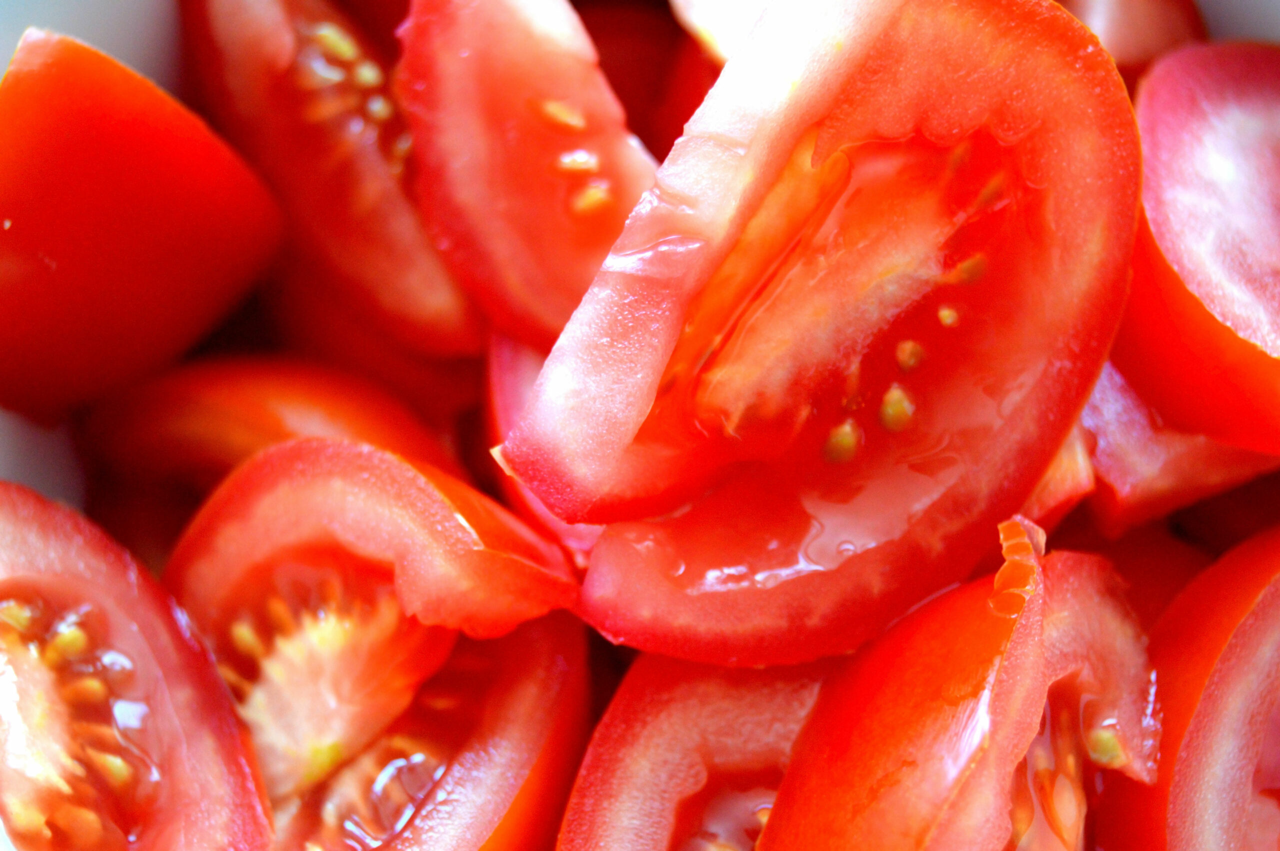 Primer plano de varios tomates rojos cortados mostrando la pulpa interior y las semillas