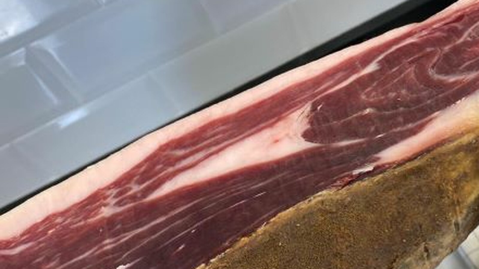 Pieza de jamón ibérico abierta en jamonero, sin etiquetas ni marcas visibles